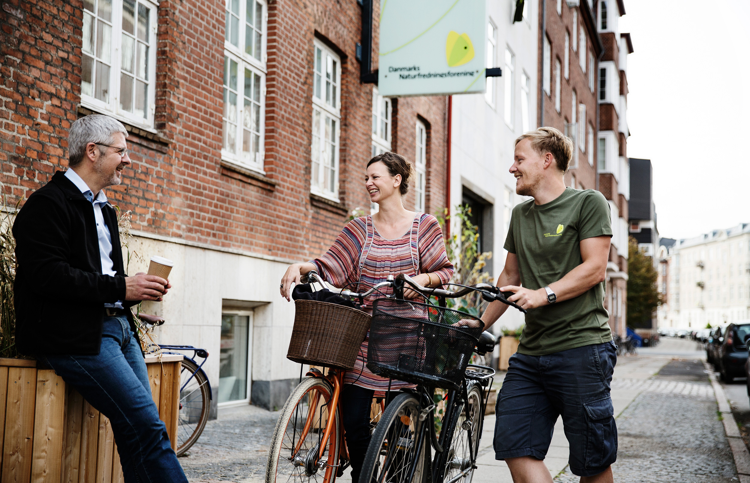 Employees with their bikes and coffee outside the office